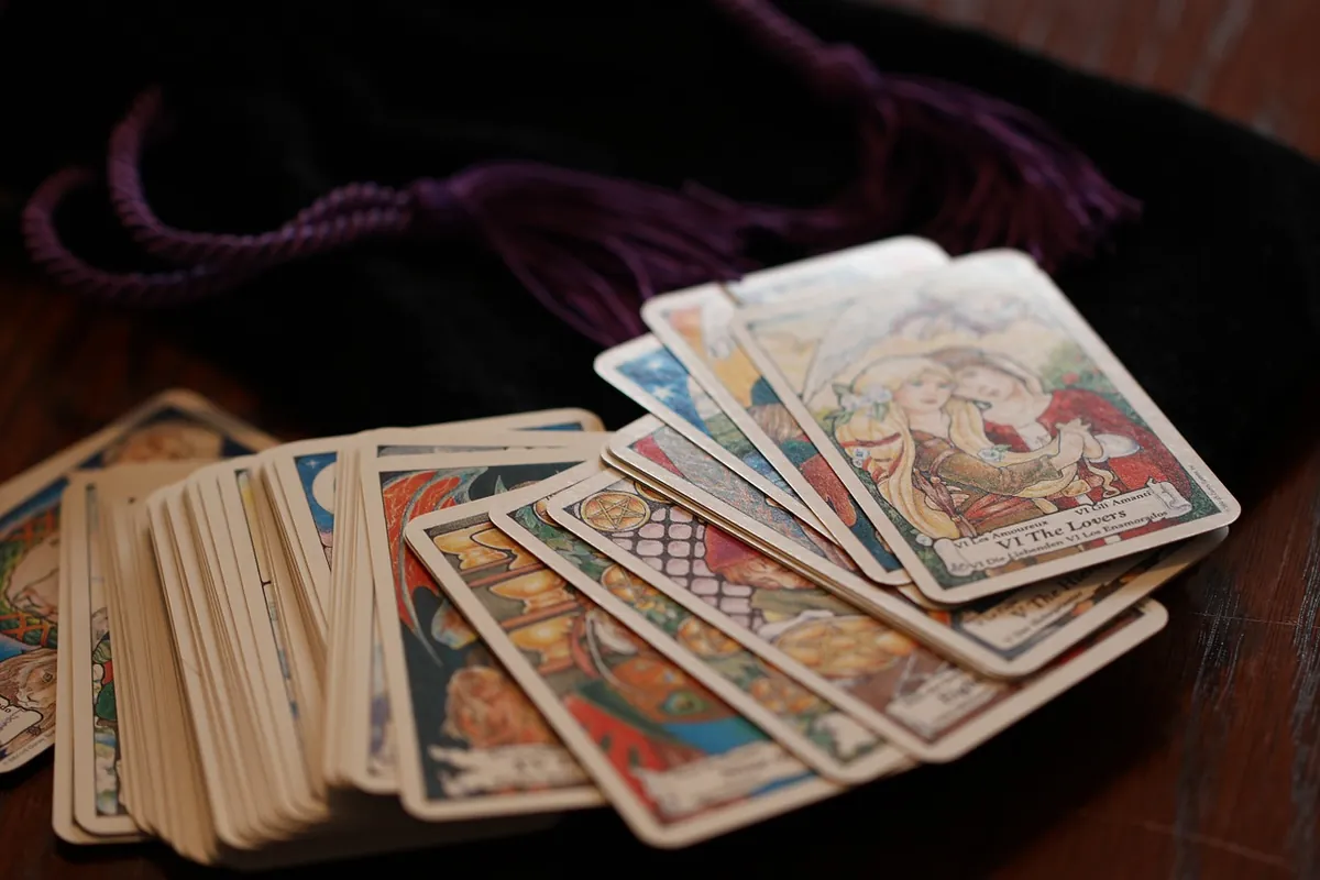 Baraja de tarot ilustrada extendida sobre madera oscura